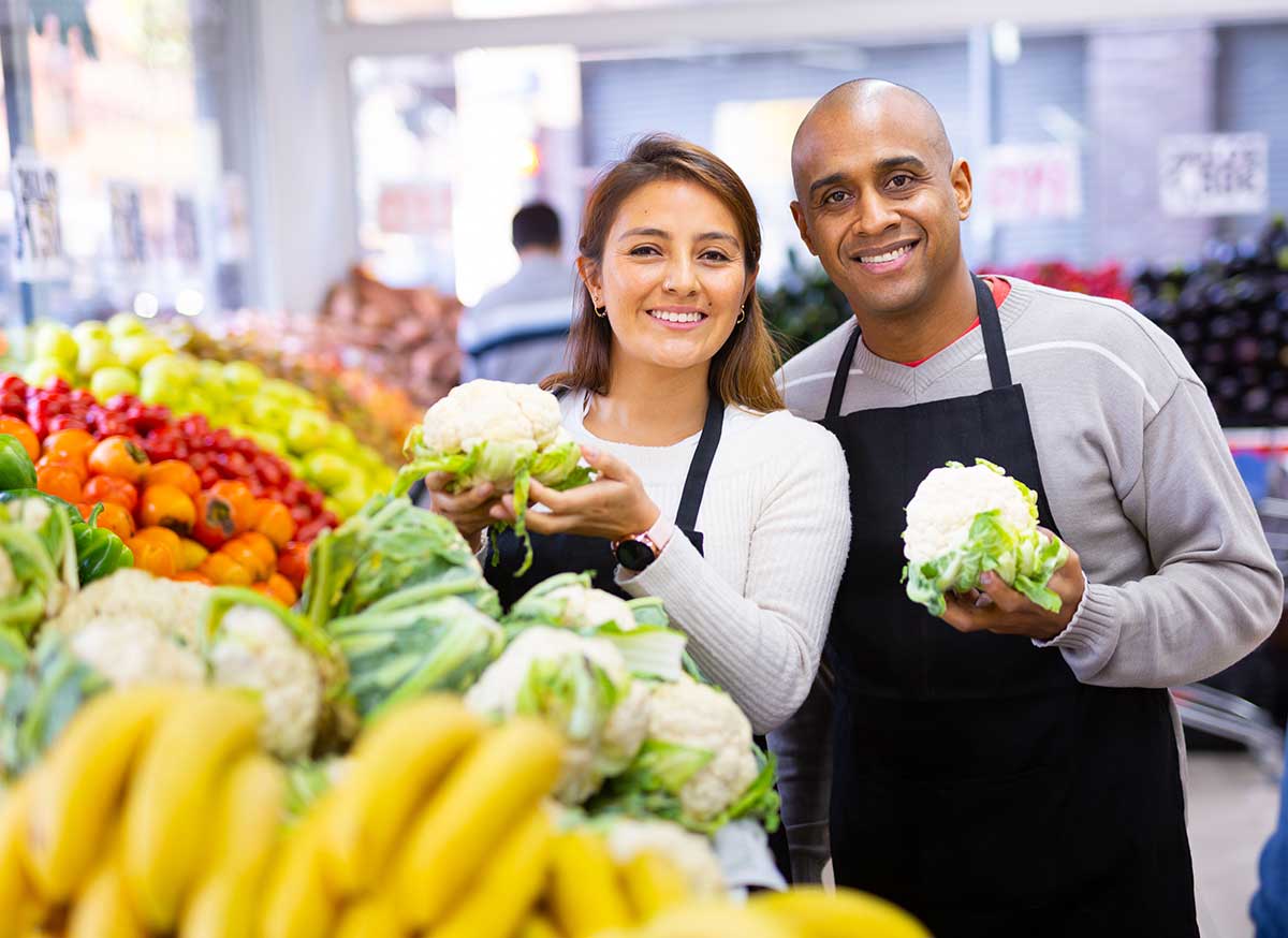 Smiling grocery associates at Southeastern Grocers stocking produce