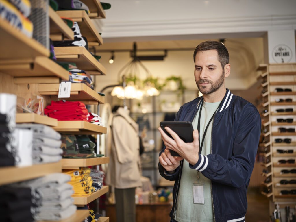 Retail employee using tablet in clothing store.
