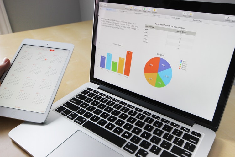 Laptop with graphs on it, and tablet opened to calendar.
