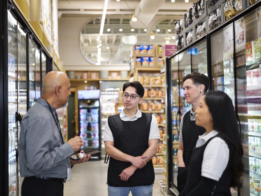 Three employees speaking to manager in a grocery store.