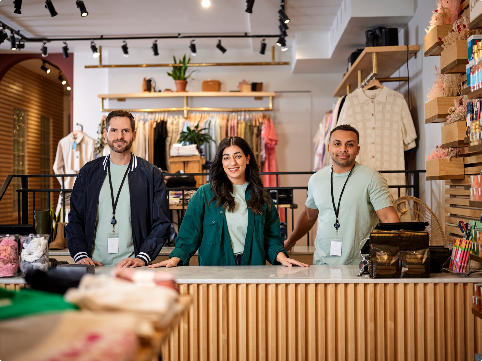 3 employees standing behind a desk in a retail store.