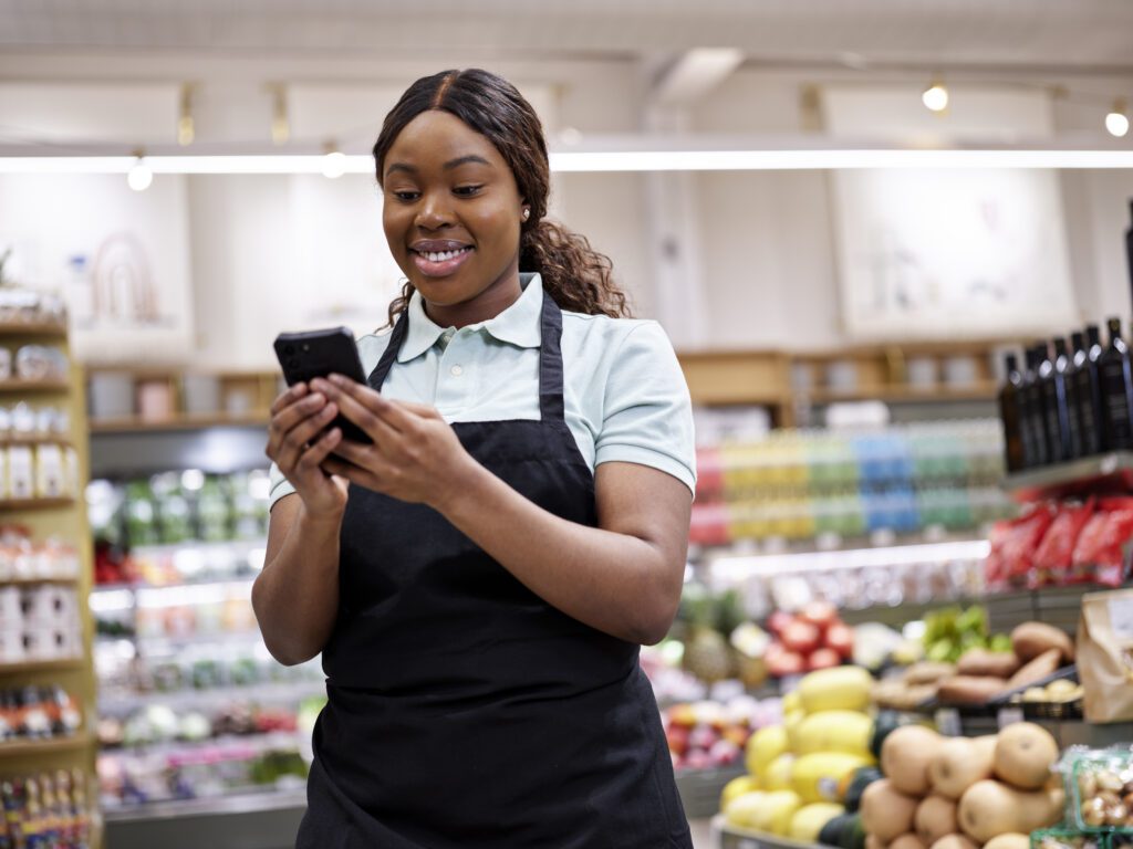 Female grocery store employee smiling at device.