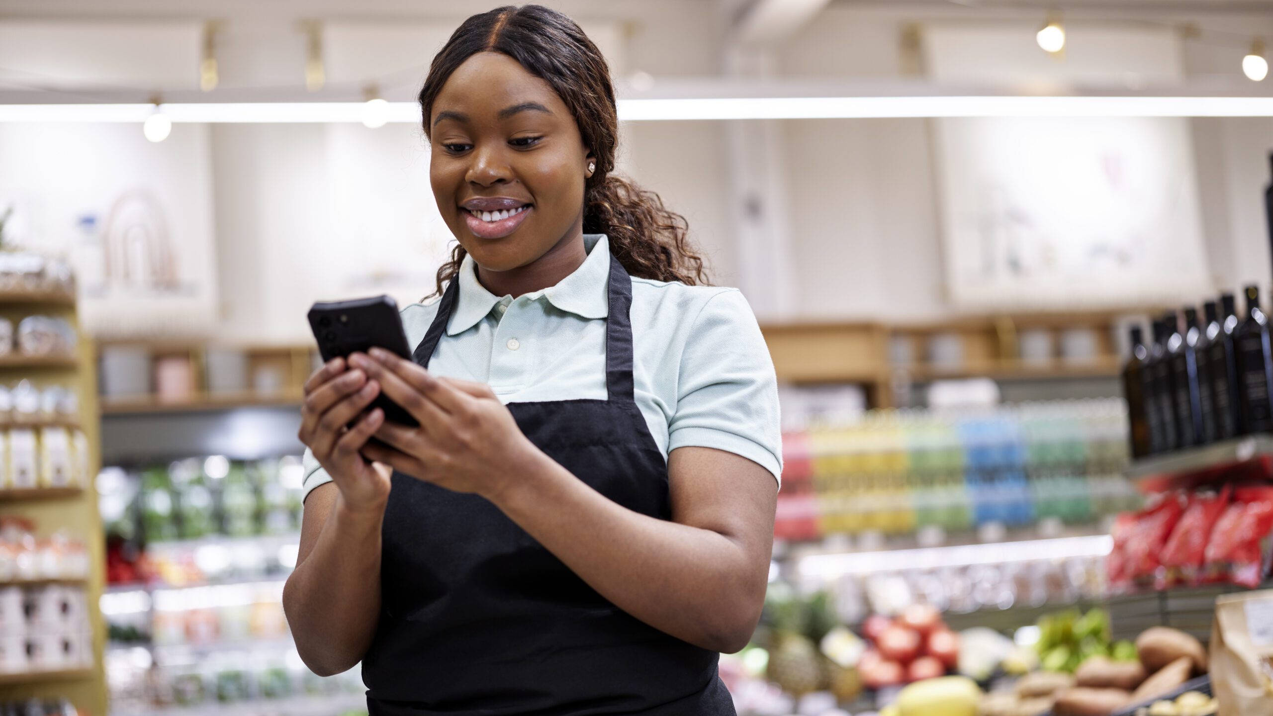 Female grocery store employee smiling at device.