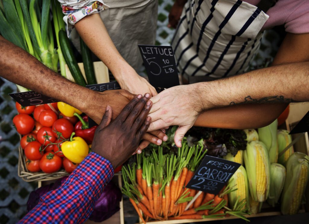 Grocery employees in a huddle putting hands in